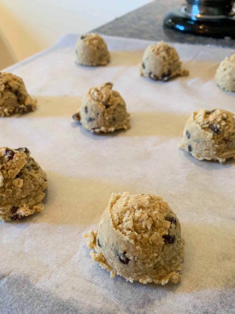 A batch of oatmeal raisin cookies, scooped on a tray and ready to be baked.