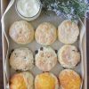 A box of assorted scones with a dish of butter and some flowers