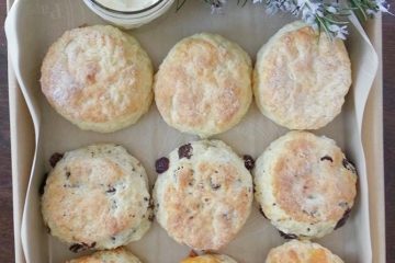 A box of assorted scones with a dish of butter and some flowers