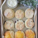 A box of assorted scones with a dish of butter and some flowers