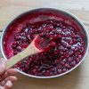 a small pot of cranberry sauce with a wooden spoon.