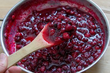 a small pot of cranberry sauce with a wooden spoon.