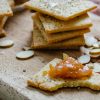 Almond Parmesan crackers with chutney on a wooden serving board