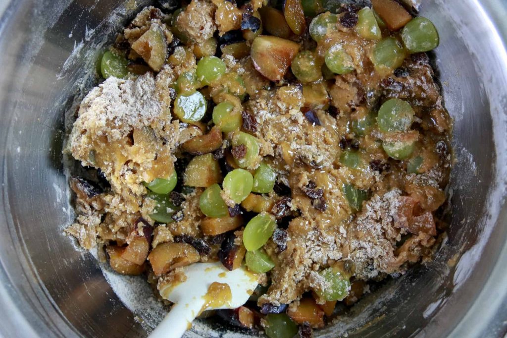 Cake batter and fresh fruit being folded together in a mixing bowl