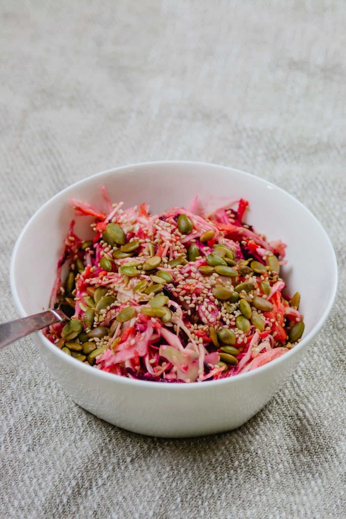 Quick veggie slaw with miso sesame dressing, in a white bowl.