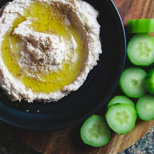 a plate of white bean hummus with sliced cucumbers on the side.