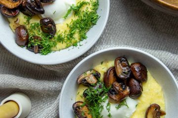 two bowls of polenta topped with poached eggs, roasted mushrooms and fresh dill