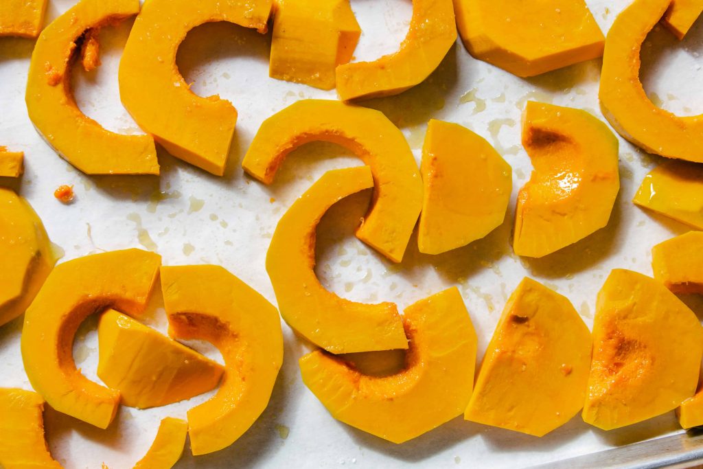 slices of kabocha squash on a baking sheet, about to be roasted