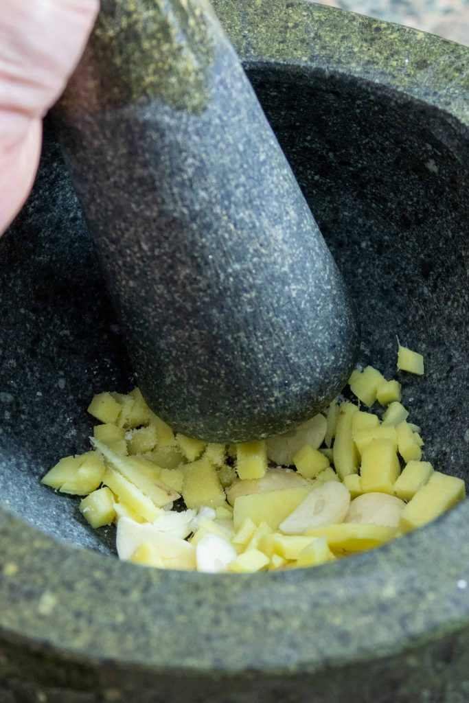Smashing ginger and garlic in a mortar and pestle