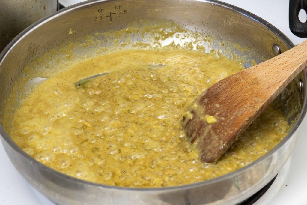 a shallow pan of simmering green curry sauce