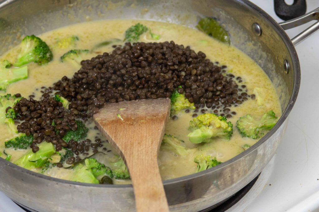 black lentils cooking in a pot of green curry
