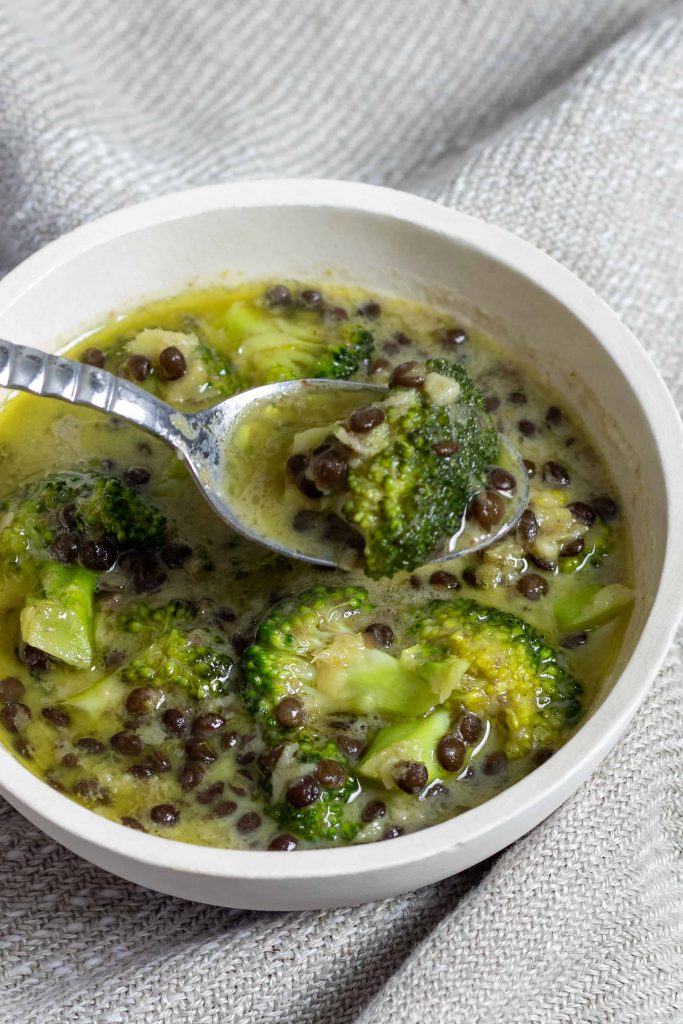 A bowl of thai green curry with lentils and broccoli
