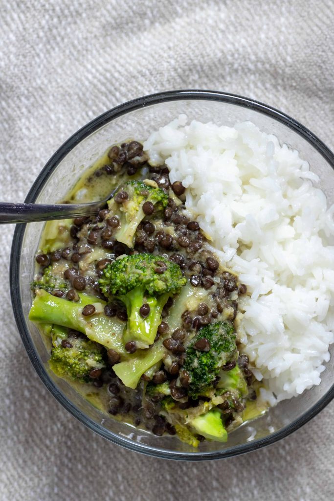 a bowl of black lentil and broccoli curry with steamed jasmine rice
