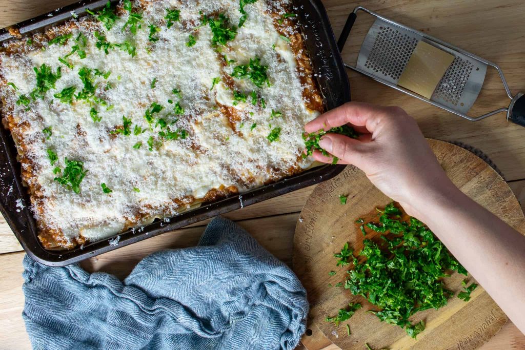 Sprinkling parsley on top of the lasagna.