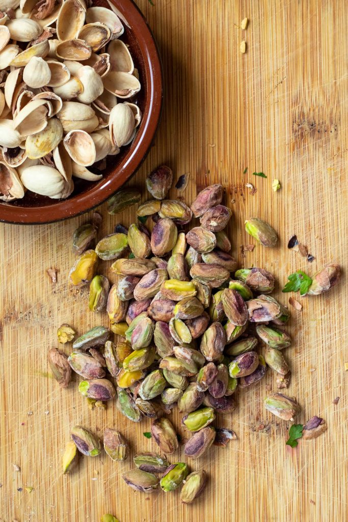 a pile of shelled pistachios with the shells next to it.