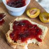 plum and ginger jam on toast with a cut fresh plum next to it.