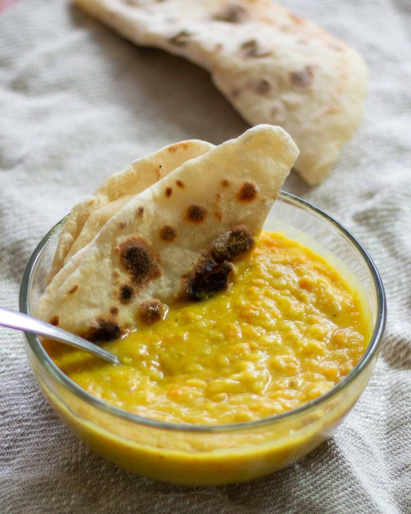 a bowl of carrot ginger lentil soup with a side of flatbread