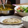 flatbread, curry, and salad laid out on a table.