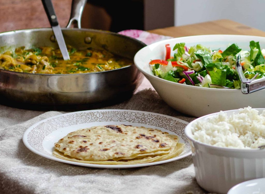 flatbread, curry, and salad laid out on a table.