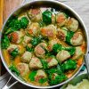 a pan of turkey meatballs in broth with wilted spinach.