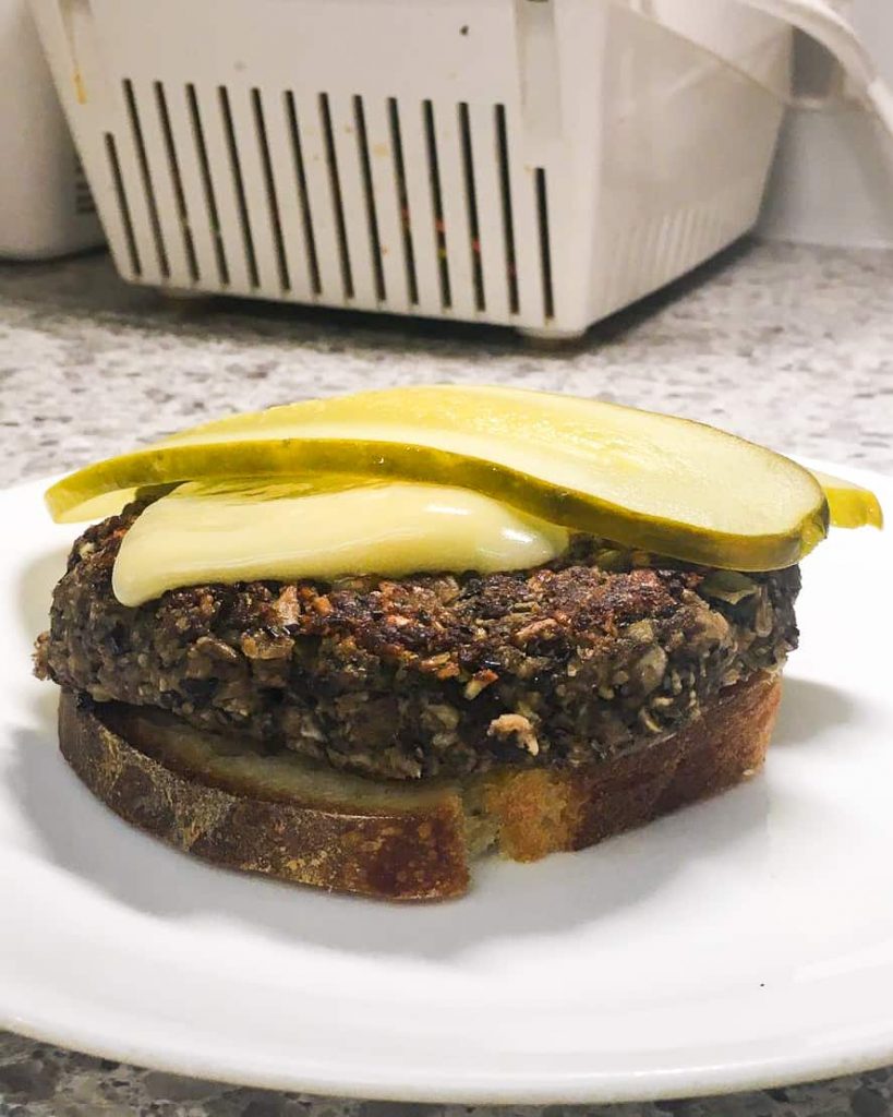 a gluten-free mushroom patty on toast with pickles.