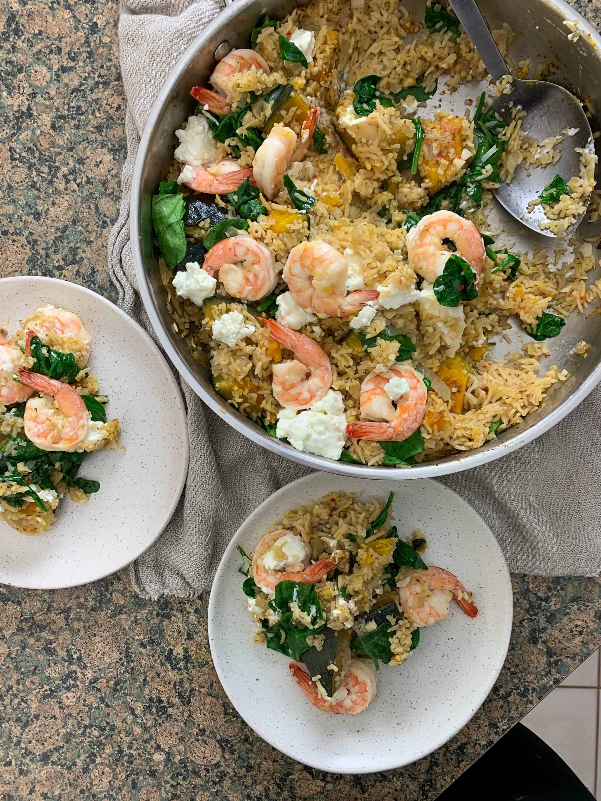 a pan and two plates with baked rice and prawns.