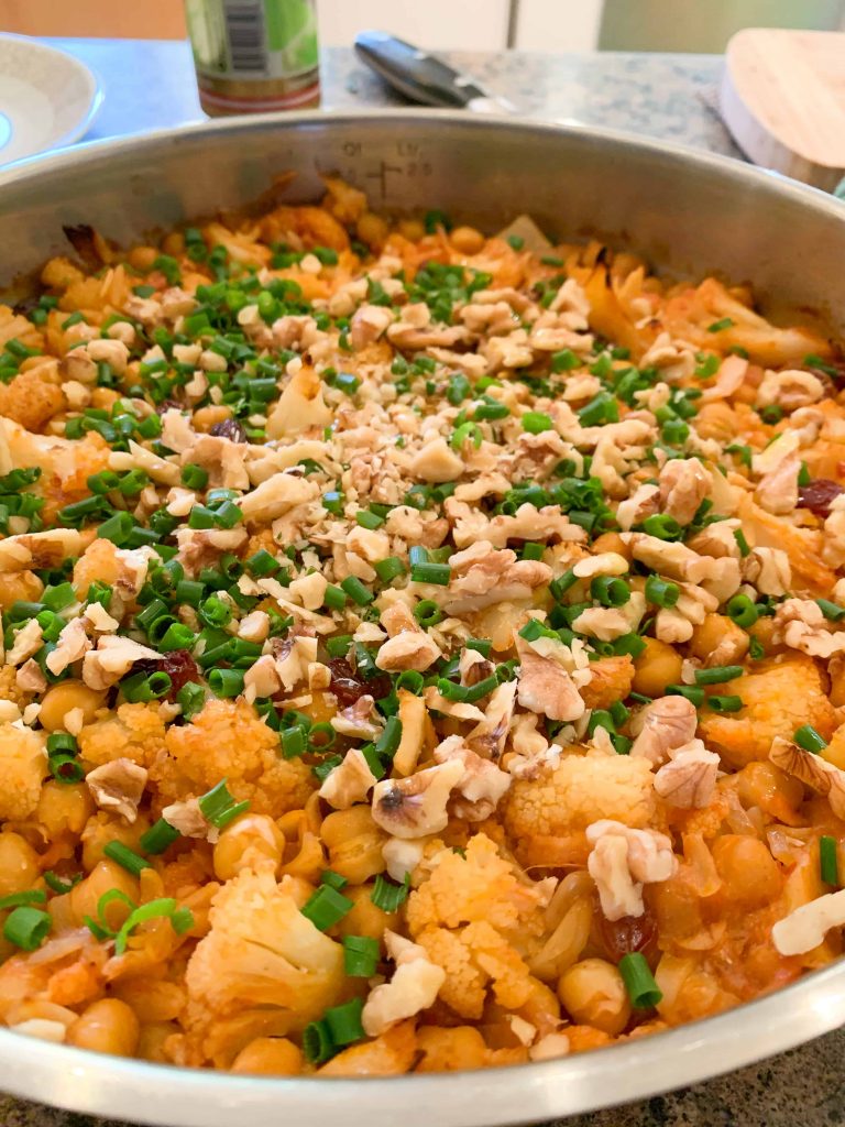 a pan of baked orzo with fresh herbs on top.