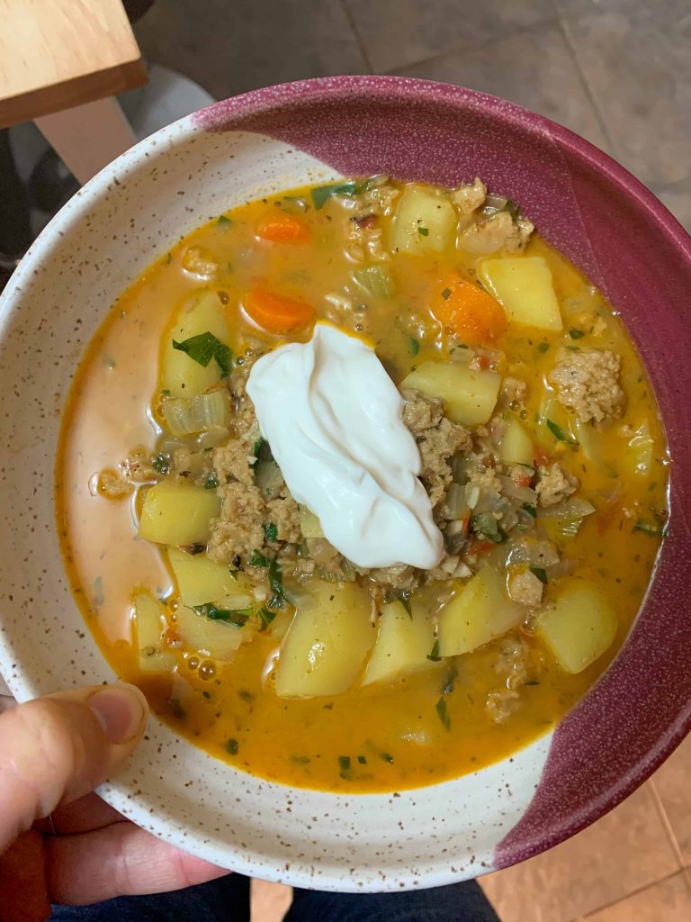 a bowl of creamy sausage and potato soup with sour cream on top.