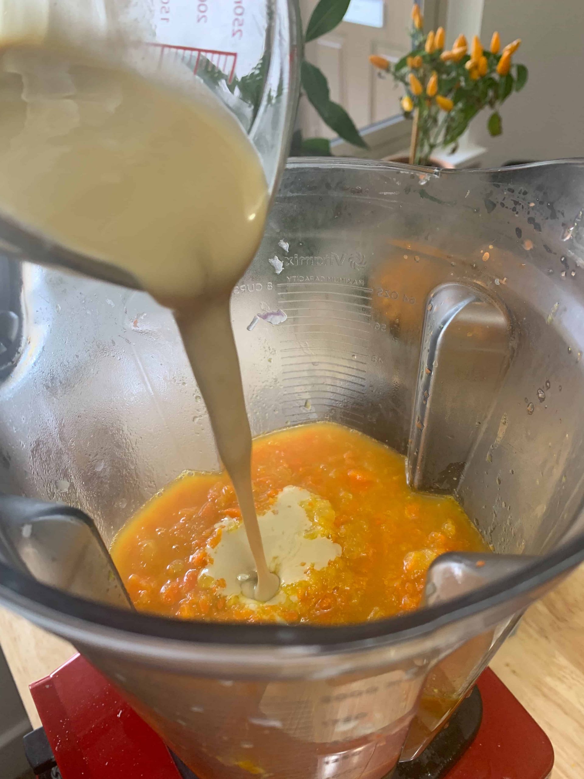 Adding tahini to carrot tahini soup in a blender.