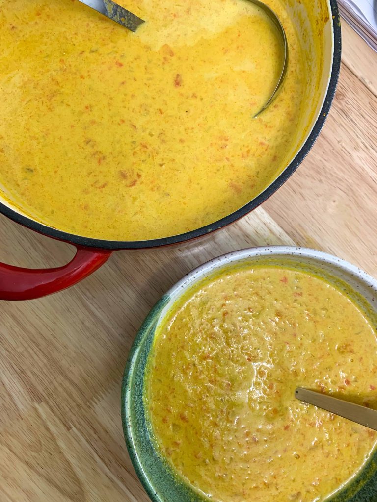 Carrot tahini soup in bowl and pot.