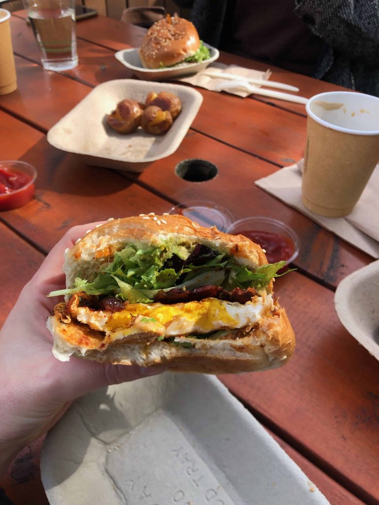 a woman's hand holding a well eaten kimchi egg sandwich.