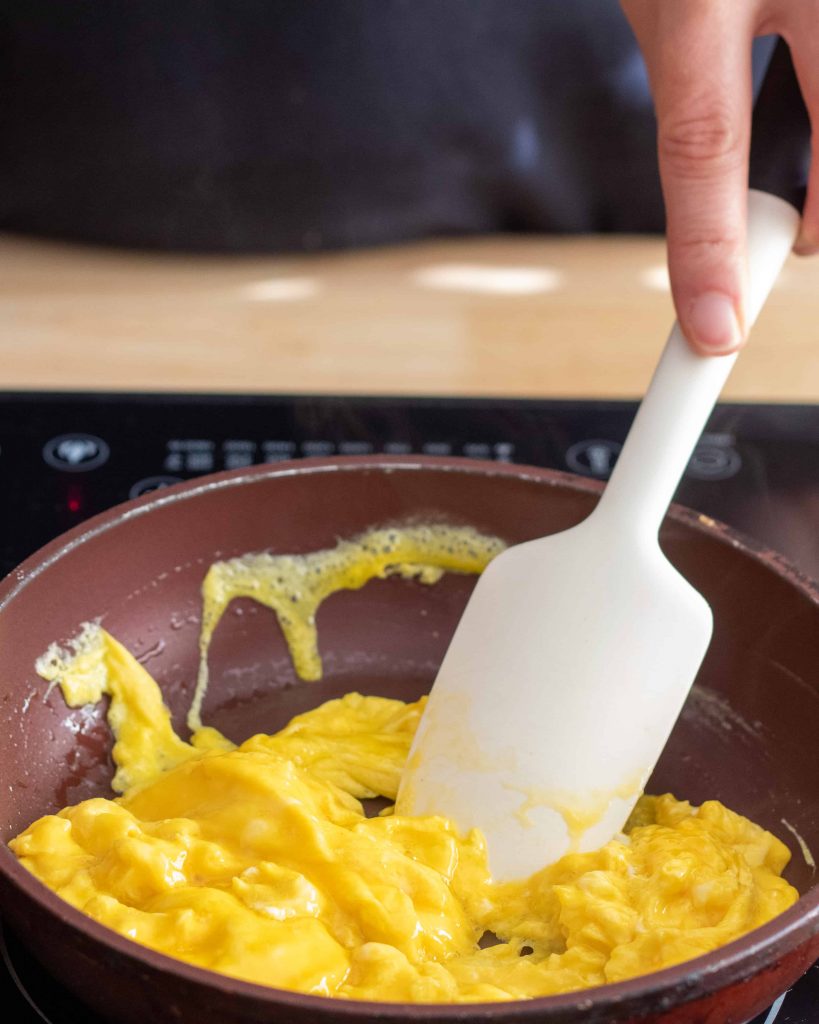 cooking scrambled eggs and stirring with a rubber spatula