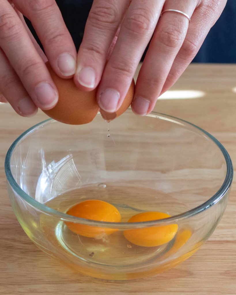 cracking eggs into a glass bowl.