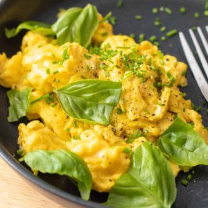 scrambled eggs with fresh herbs on a plate.