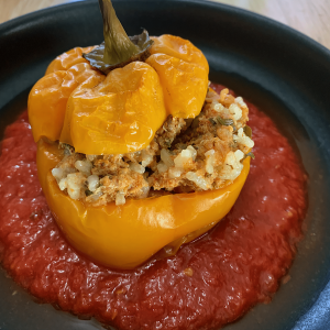 stuffed pepper on a plate with tomato sauce.