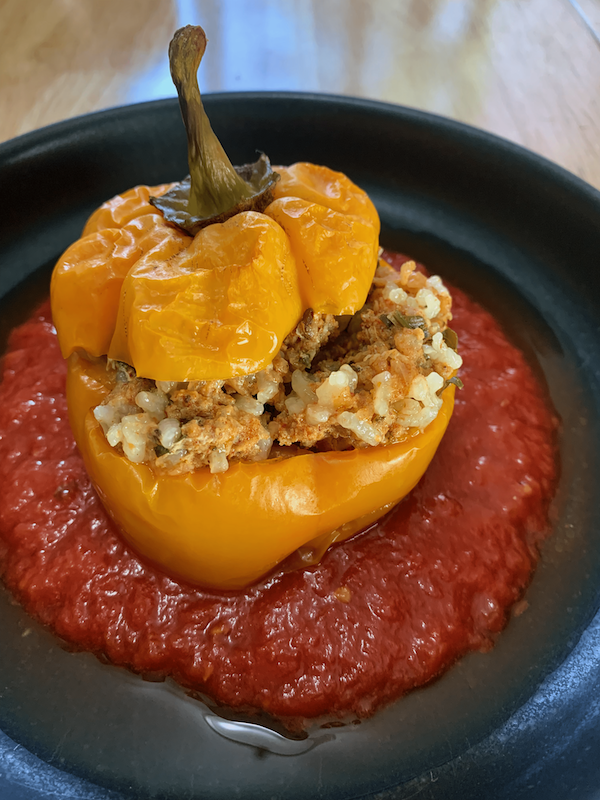 stuffed pepper on a plate with tomato sauce.
