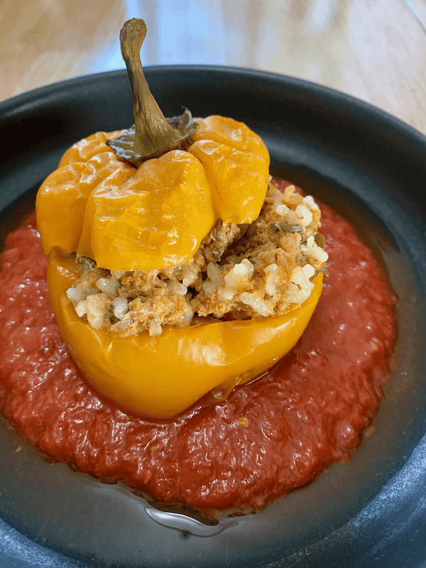 stuffed pepper on a plate with tomato sauce.