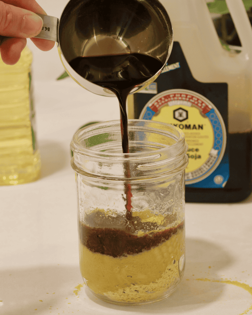 Adding soy sauce to a jar with nutritional yeast.