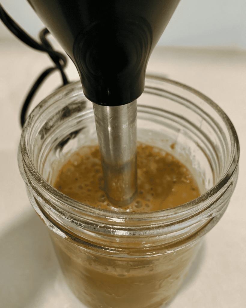 Blending nutritional yeast dressing with an immersion blender.