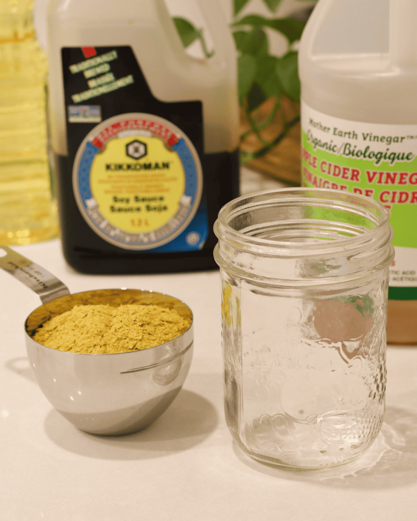 Nutritional yeast in a measuring cup next to an empty mason jar.