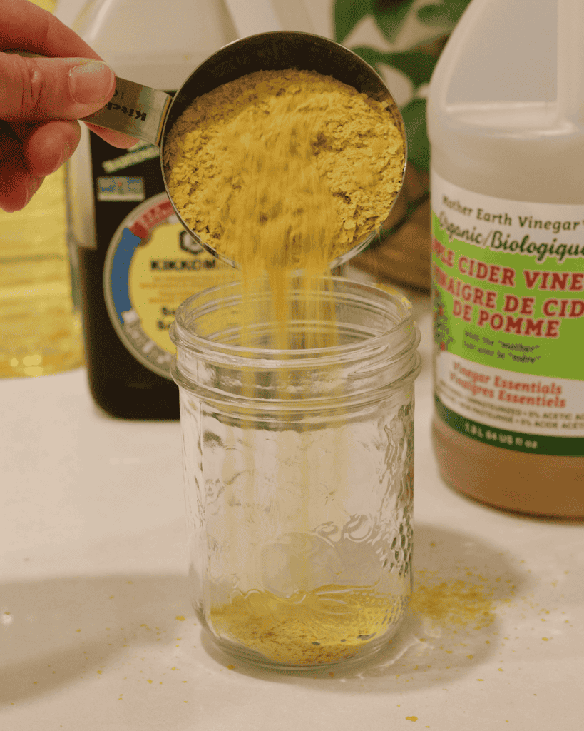 Adding nutritional yeast to a mason jar.