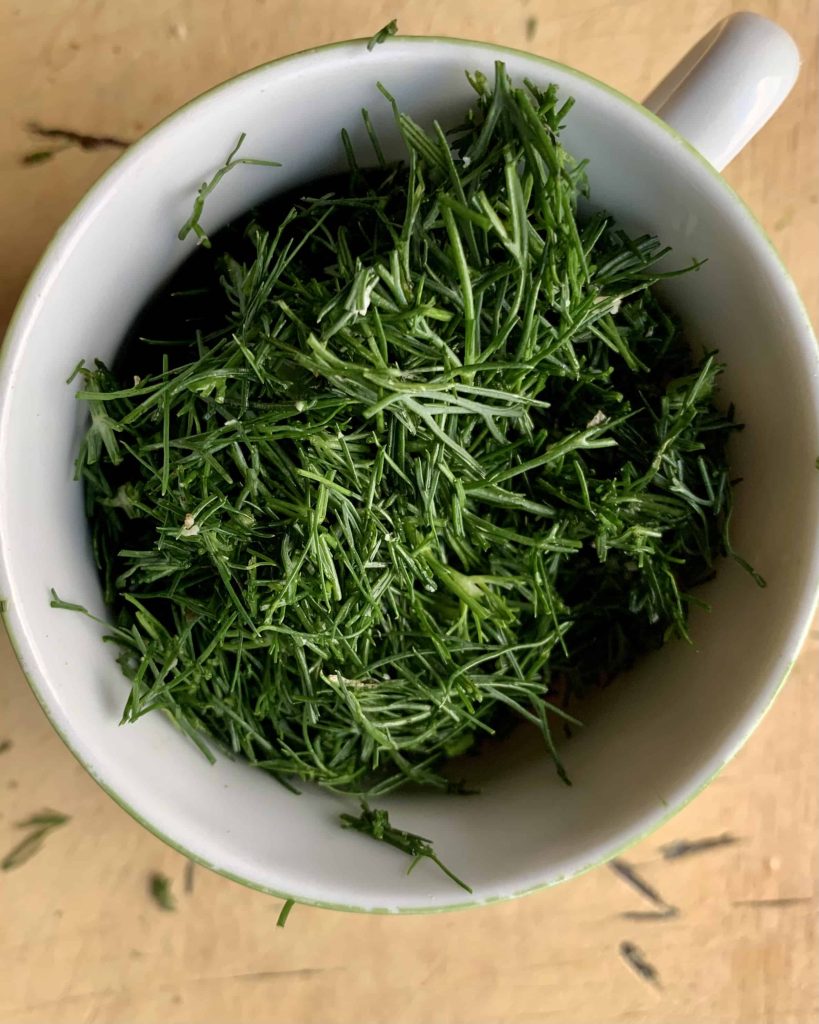 Chopped fresh dill in a measuring cup.
