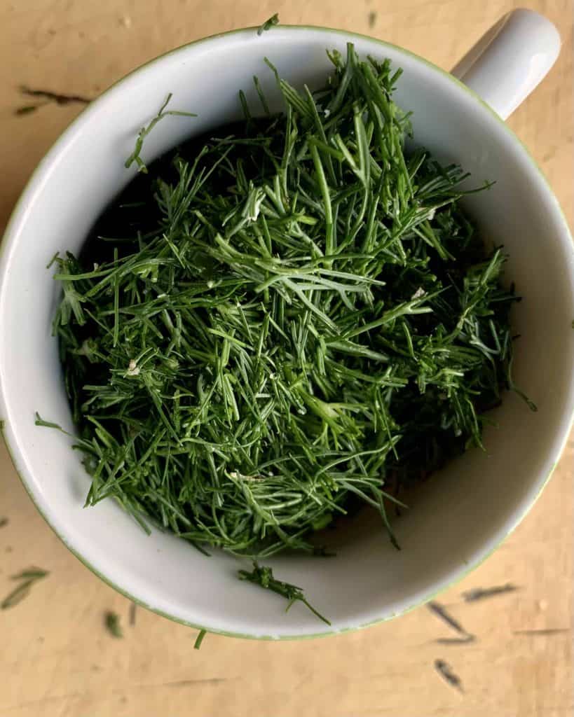 Chopped fresh dill in a measuring cup.