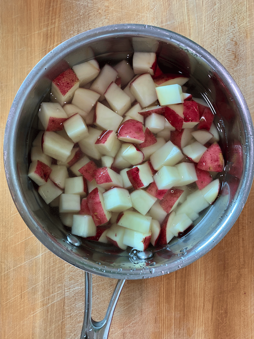 Diced potatoes in a small pot with water.