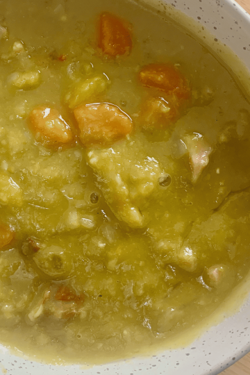 A closeup shot of a bowl of split pea and ham soup.