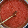 A pan of hearty marinara sauce with a wooden spoon.