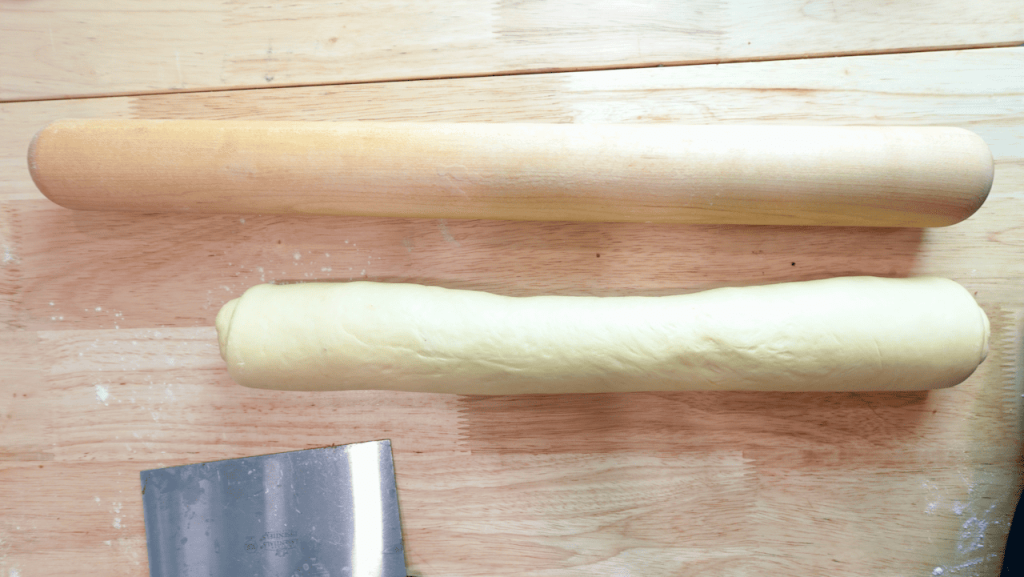Cinnamon roll log next to a rolling pin.