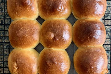 Close up shot of freshly baked dinner rolls, cooling on a rack.
