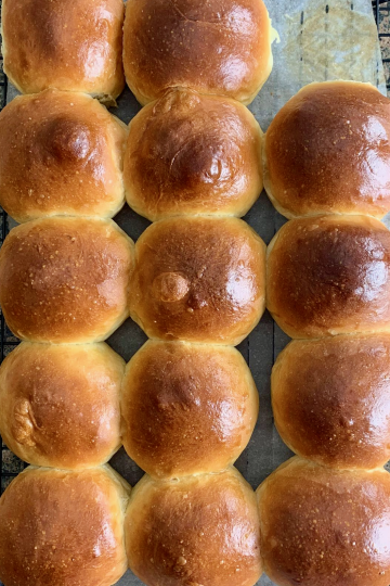 Close up shot of freshly baked dinner rolls, cooling on a rack.