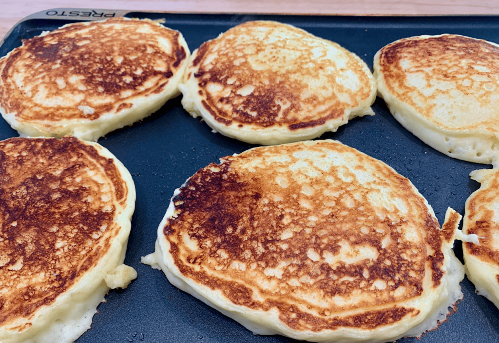 Cottage cheese pancakes cooking on griddle.